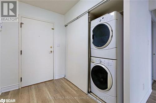 Laundry room featuring stacked washing maching and dryer and light hardwood / wood-style flooring - 135 Hillcrest Avenue Unit# 1013, Mississauga, ON - Indoor Photo Showing Laundry Room