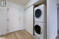 Laundry room featuring stacked washing maching and dryer and light hardwood / wood-style flooring - 