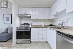 Kitchen featuring light stone countertops, appliances with stainless steel finishes, backsplash, sink, and white cabinets - 