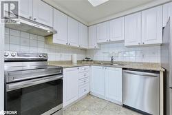 Kitchen featuring light stone countertops, sink, stainless steel appliances, backsplash, and white cabinets - 