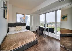 Bedroom featuring multiple windows and dark wood-type flooring - 