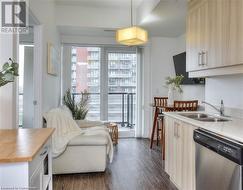 Kitchen featuring stainless steel dishwasher, dark wood-type flooring, sink, pendant lighting, and butcher block countertops - 