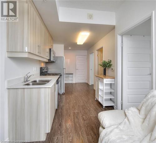 Kitchen featuring dark hardwood / wood-style flooring, light brown cabinetry, sink, and appliances with stainless steel finishes - 160 King Street N Unit# 901, Waterloo, ON - Indoor Photo Showing Kitchen With Double Sink