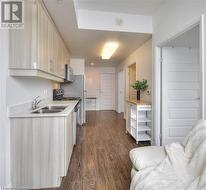 Kitchen featuring dark hardwood / wood-style flooring, light brown cabinetry, sink, and appliances with stainless steel finishes - 