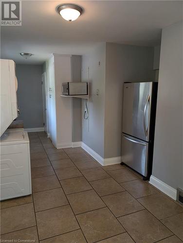 Kitchen featuring white cabinets, stainless steel fridge, and dark tile patterned floors - 175 Oxford Street Unit# A, Kitchener, ON - Indoor