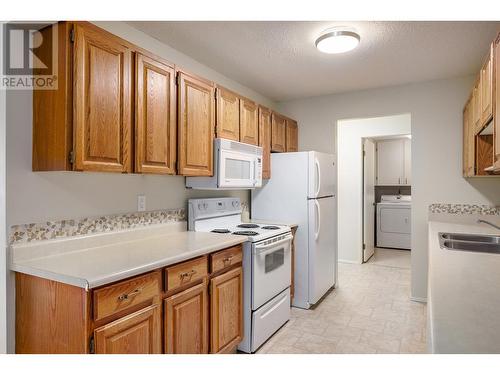 The first thing you will notice is an immaculate kitchen with pristine appliances & oak wood cabinetry - 2085 Gordon Drive Unit# 215, Kelowna, BC - Indoor Photo Showing Kitchen With Double Sink