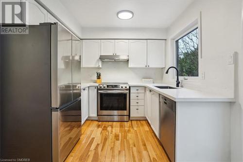 Kitchen with white cabinets, appliances with stainless steel finishes, light hardwood / wood-style floors, and sink - 5021 Bunton Crescent, Burlington, ON - Indoor Photo Showing Kitchen With Stainless Steel Kitchen With Upgraded Kitchen