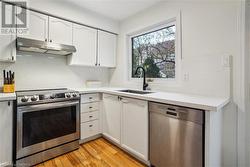 Kitchen featuring white cabinets, light wood-type flooring, sink, and appliances with stainless steel finishes - 