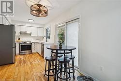 Kitchen with light hardwood / wood-style floors, sink, white cabinetry, and stainless steel appliances - 