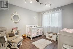 Bedroom with dark hardwood / wood-style floors and a nursery area - 