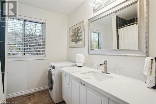 Laundry area featuring cabinets, separate washer and dryer, a wealth of natural light, and sink - 5021 Bunton Crescent, Burlington, ON - Indoor Photo Showing Laundry Room