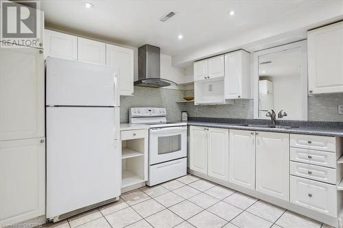 Kitchen with white cabinets, white appliances, and wall chimney range hood - 5021 Bunton Crescent, Burlington, ON - Indoor Photo Showing Kitchen