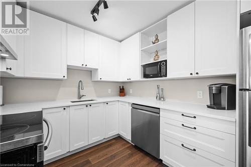 Kitchen with rail lighting, stainless steel appliances, dark wood-type flooring, sink, and white cabinetry - 305 East 24Th Street, Hamilton, ON - Indoor Photo Showing Kitchen