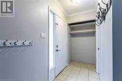 Doorway to outside featuring light tile patterned floors, a textured ceiling, and ornamental molding - 