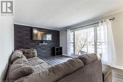 Living room featuring ornamental molding, a textured ceiling, and hardwood / wood-style flooring - 