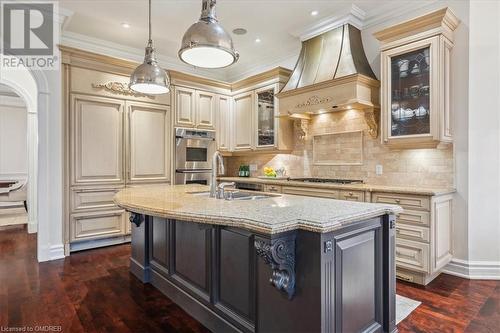 Kitchen with light stone countertops, sink, an island with sink, and dark wood-type flooring - 1143 Riverbank Way, Oakville, ON 