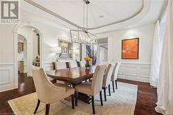 Dining room featuring a chandelier, a tray ceiling, and dark wood-type flooring - 