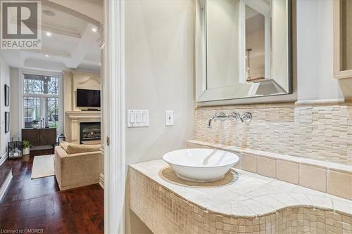 Bathroom with hardwood / wood-style floors, backsplash, coffered ceiling, sink, and a large fireplace - 1143 Riverbank Way, Oakville, ON 