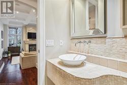 Bathroom with hardwood / wood-style floors, backsplash, coffered ceiling, sink, and a large fireplace - 