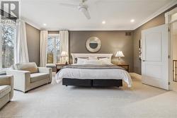 Bedroom with light colored carpet, ceiling fan, and crown molding - 