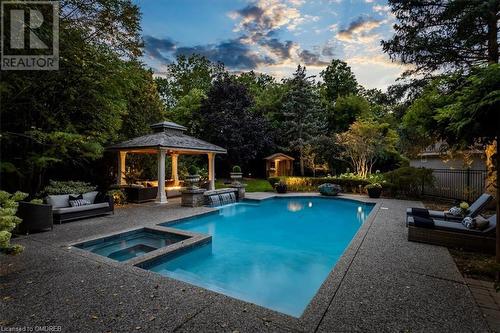 Pool at dusk with a gazebo, an outdoor living space, a patio, and an in ground hot tub - 1143 Riverbank Way, Oakville, ON 