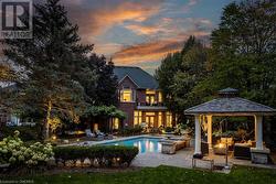 Pool at dusk with a gazebo, an outdoor living space, a patio area, and a lawn - 