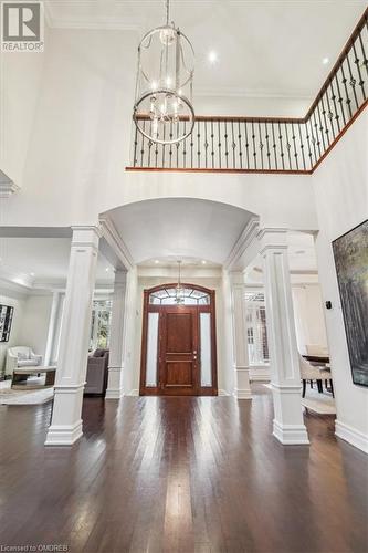 Entrance foyer featuring ornate columns, dark wood-type flooring, and a chandelier - 1143 Riverbank Way, Oakville, ON 