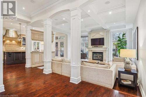 Living room with beam ceiling, dark wood-type flooring, coffered ceiling, crown molding, and a fireplace - 1143 Riverbank Way, Oakville, ON 