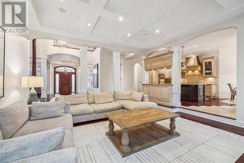 Living room featuring beamed ceiling, light hardwood / wood-style floors, ornate columns, and coffered ceiling - 1143 Riverbank Way, Oakville, ON 