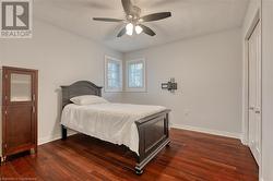 Bedroom with a textured ceiling, dark hardwood / wood-style flooring, a closet, and ceiling fan - 