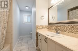 Full bathroom with tile patterned flooring, toilet, decorative backsplash, vanity, and shower / tub combo - 