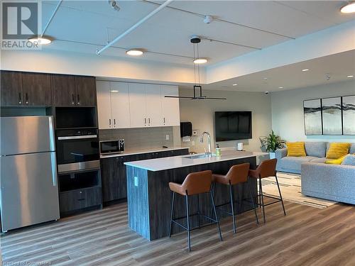 Kitchen featuring white cabinets, a center island with sink, sink, dark brown cabinets, and stainless steel appliances - 28 Westhill Drive Unit# 206, Waterloo, ON - Indoor Photo Showing Kitchen With Stainless Steel Kitchen