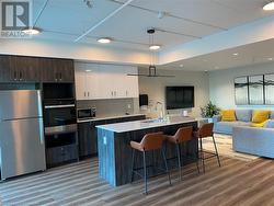 Kitchen featuring white cabinets, a center island with sink, sink, dark brown cabinets, and stainless steel appliances - 