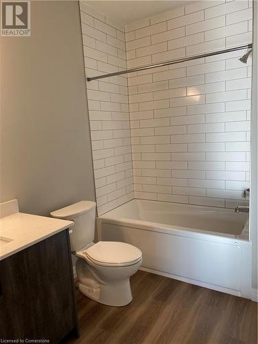 Full bathroom with hardwood / wood-style floors, vanity, toilet, and tiled shower / bath combo - 28 Westhill Drive Unit# 206, Waterloo, ON - Indoor Photo Showing Bathroom