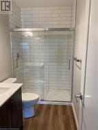 Bathroom featuring an enclosed shower, vanity, toilet, and wood-type flooring - 