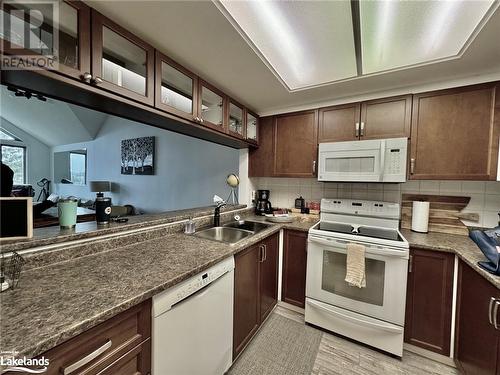 Kitchen with decorative backsplash, white appliances, dark brown cabinetry, sink, and light hardwood / wood-style floors - 231 Grandview/Hilltop Drive, Huntsville, ON - Indoor Photo Showing Kitchen With Double Sink