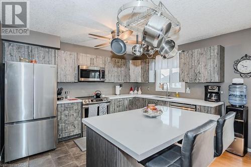 Kitchen with a textured ceiling, a center island, stainless steel appliances, and sink - 727 Zermatt Drive, Waterloo, ON - Indoor