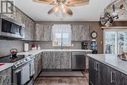 Kitchen featuring a wealth of natural light, sink, stainless steel appliances, and dark tile patterned flooring - 