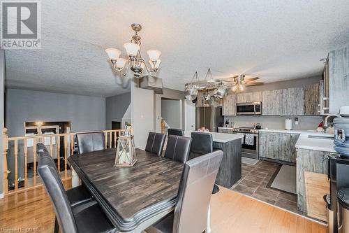 Dining room featuring a textured ceiling, ceiling fan with notable chandelier, sink, and dark wood-type flooring - 727 Zermatt Drive, Waterloo, ON - Indoor Photo Showing Dining Room