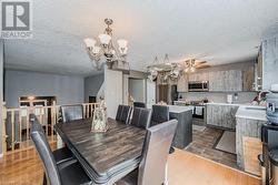 Dining room featuring a textured ceiling, ceiling fan with notable chandelier, sink, and dark wood-type flooring - 