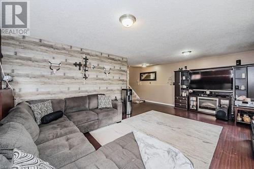 Living room featuring a textured ceiling, wooden walls, and dark wood-type flooring - 727 Zermatt Drive, Waterloo, ON - Indoor Photo Showing Living Room