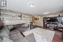 Living room featuring a textured ceiling, wooden walls, and dark wood-type flooring - 