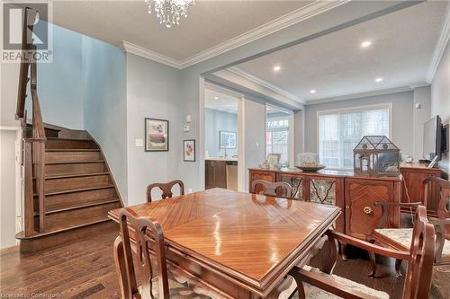 Dining room featuring a textured ceiling, ornamental molding, dark wood-type flooring, and an inviting chandelier - 26 Summerberry Way, Hamilton, ON - Indoor Photo Showing Dining Room