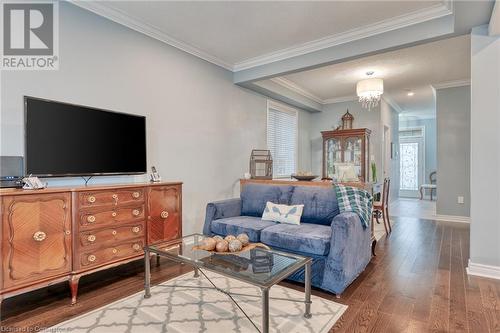 Living room with crown molding, wood-type flooring, and an inviting chandelier - 26 Summerberry Way, Hamilton, ON - Indoor Photo Showing Living Room