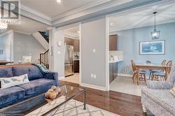 Living room with light hardwood / wood-style flooring, crown molding, and a notable chandelier - 