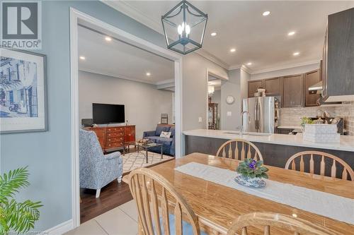 Dining space with sink, light wood-type flooring, ornamental molding, and a notable chandelier - 26 Summerberry Way, Hamilton, ON - Indoor Photo Showing Other Room