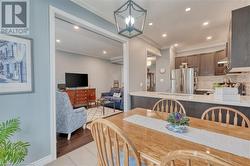 Dining space with sink, light wood-type flooring, ornamental molding, and a notable chandelier - 