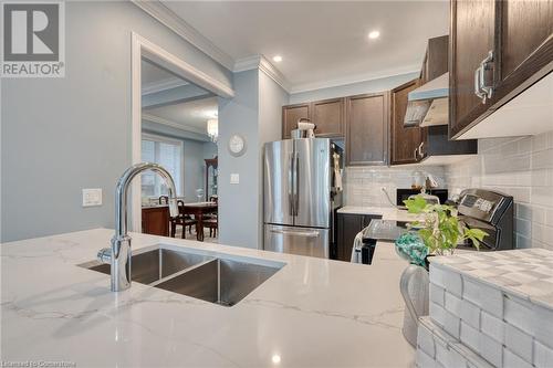 Kitchen with stainless steel fridge, sink, light stone counters, and ornamental molding - 26 Summerberry Way, Hamilton, ON - Indoor Photo Showing Kitchen With Double Sink With Upgraded Kitchen