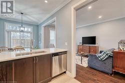 Kitchen featuring sink, dishwasher, crown molding, decorative light fixtures, and light wood-type flooring - 