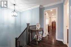 Corridor with a textured ceiling, dark wood-type flooring, a notable chandelier, and ornamental molding - 